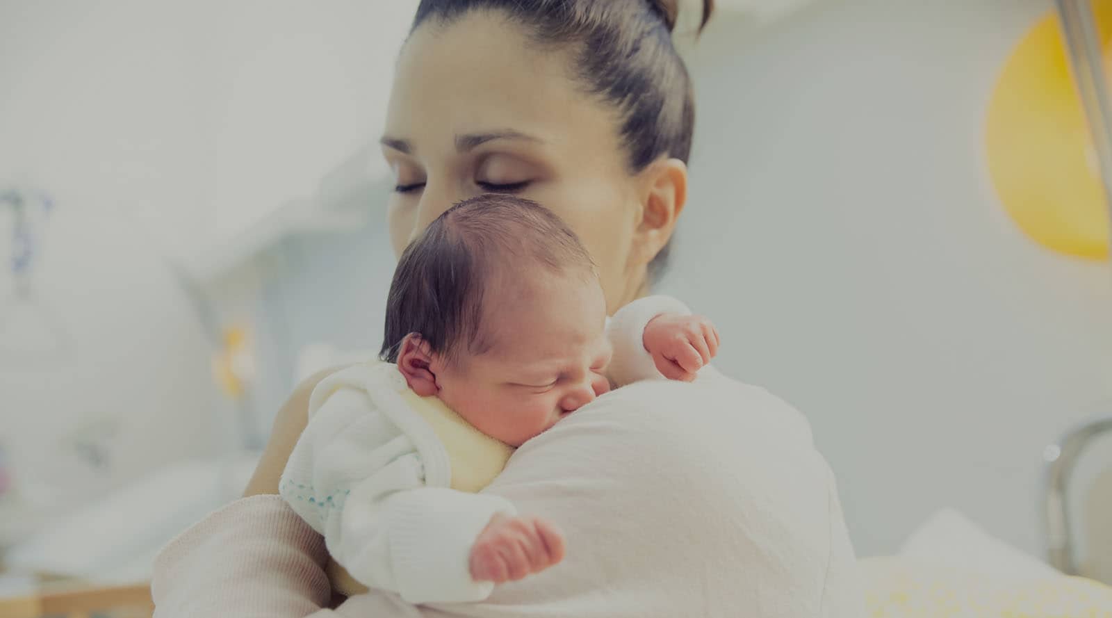 Woman cradling a newborn baby on her shoulder