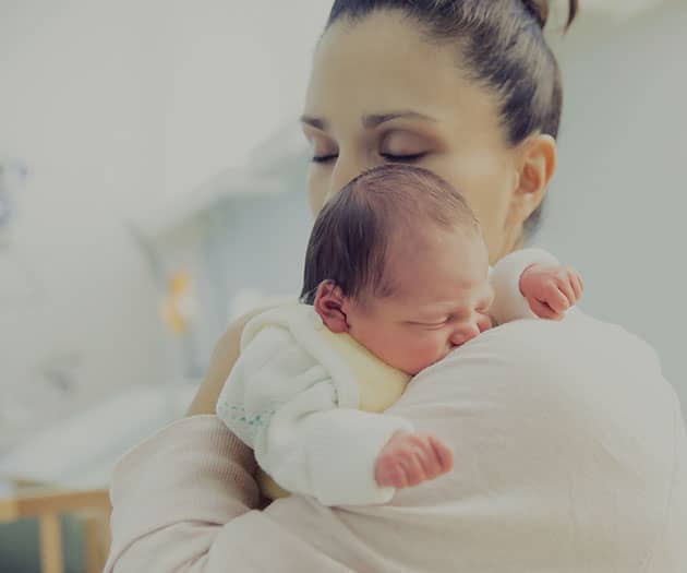 Woman cradling a newborn baby on her shoulder