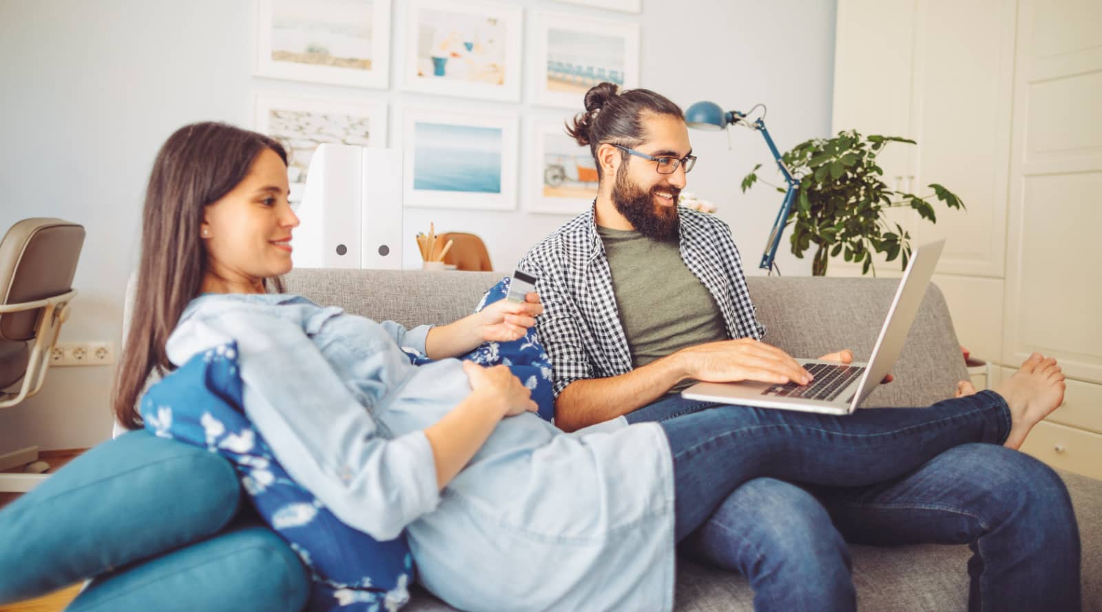 A pregnant woman and her male partner relax on the sofa