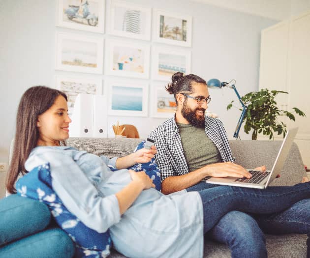 A pregnant woman and her male partner relax on the sofa