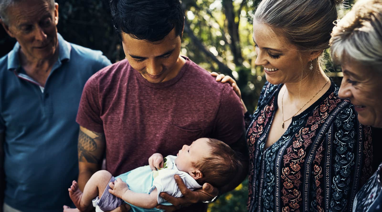 Dad holding newborn surrounded by family