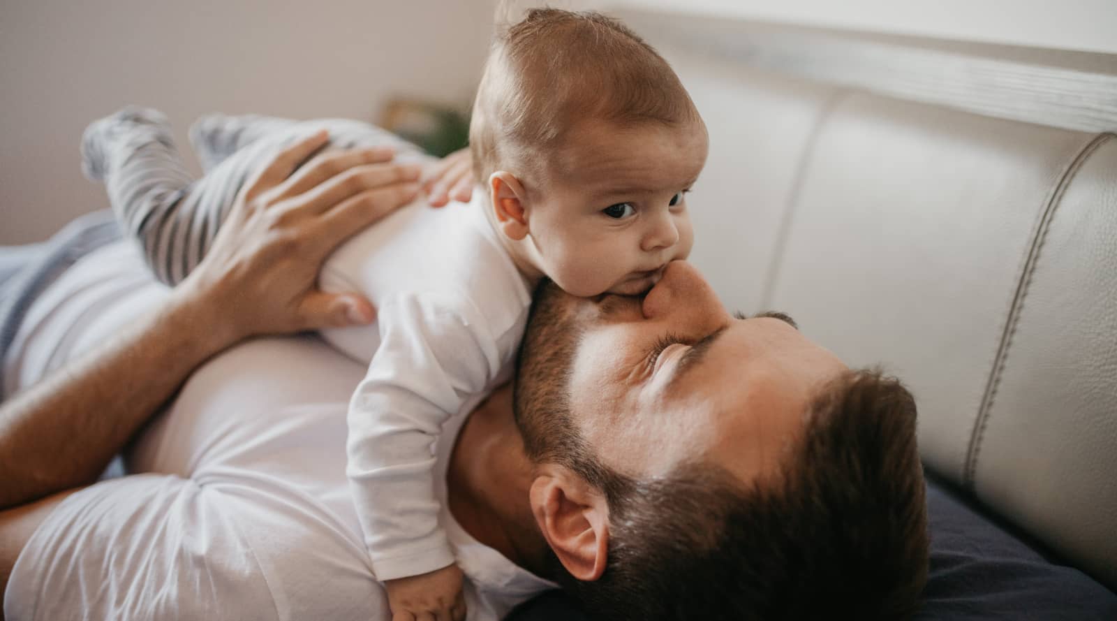 Dad laying down and kissing a baby