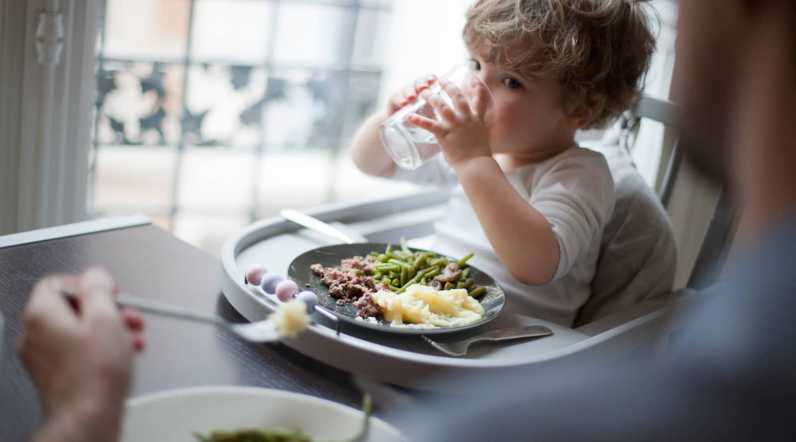 Toddler drinking water at family meal