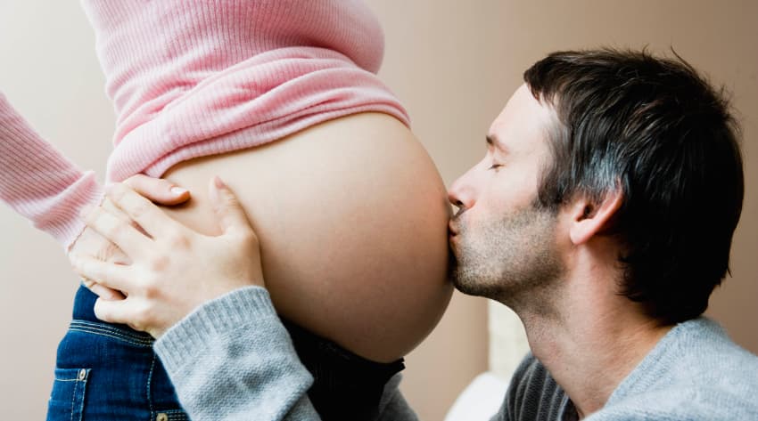 father kissing pregnant mother’s baby bump
